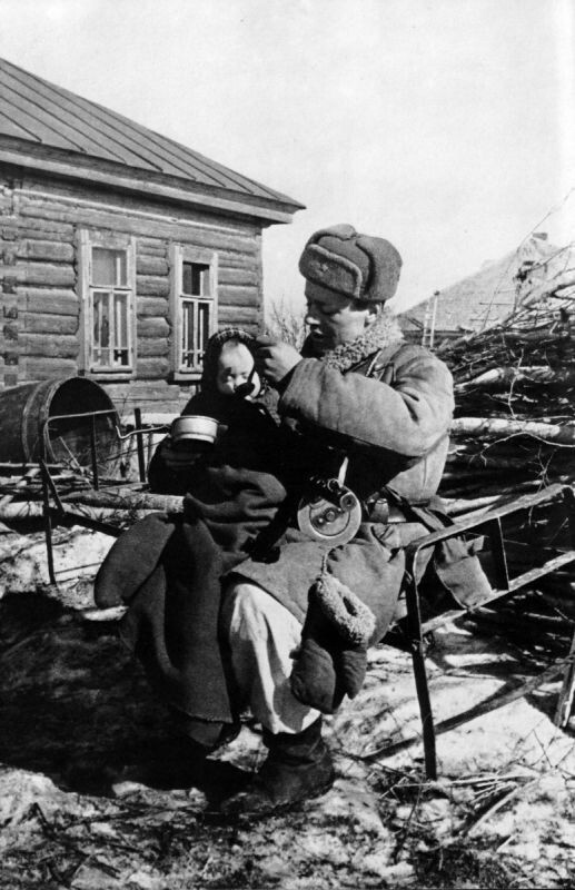 Сержант В. Моисеев кормит двухлетнюю девочку Валю, найденную им в одной из пустых изб деревни Извеково. 14 марта 1943-го года