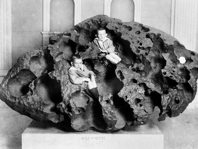 Двое детей сидят внутри Уилламетта, железного метеорита весом 14 500 кг. Это самый крупный метеорит, обнаруженный в Северной Америке, и шестой по величине в мире