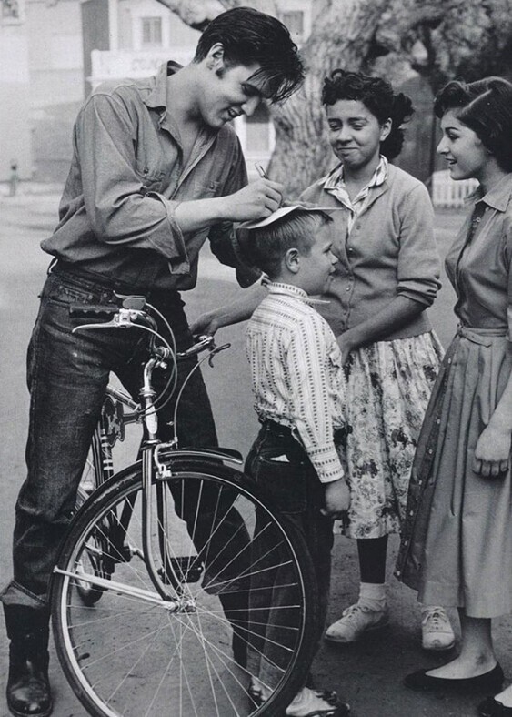 Элвис Пресли дает автограф на голове мальчика.