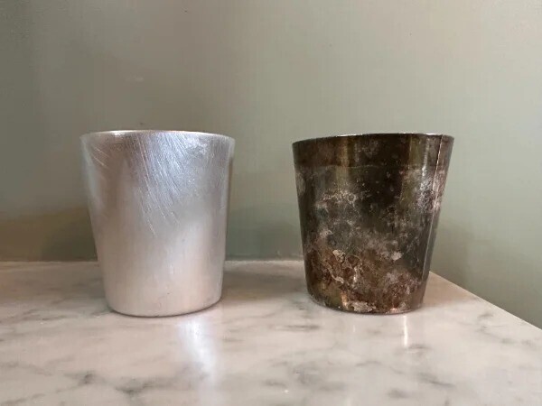 Два одинаковых серебряных стакана, один из которых покрыт налетом, а другой почищен
