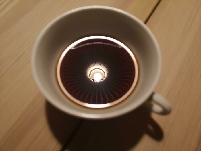 В чашке кофе отражается лампа
