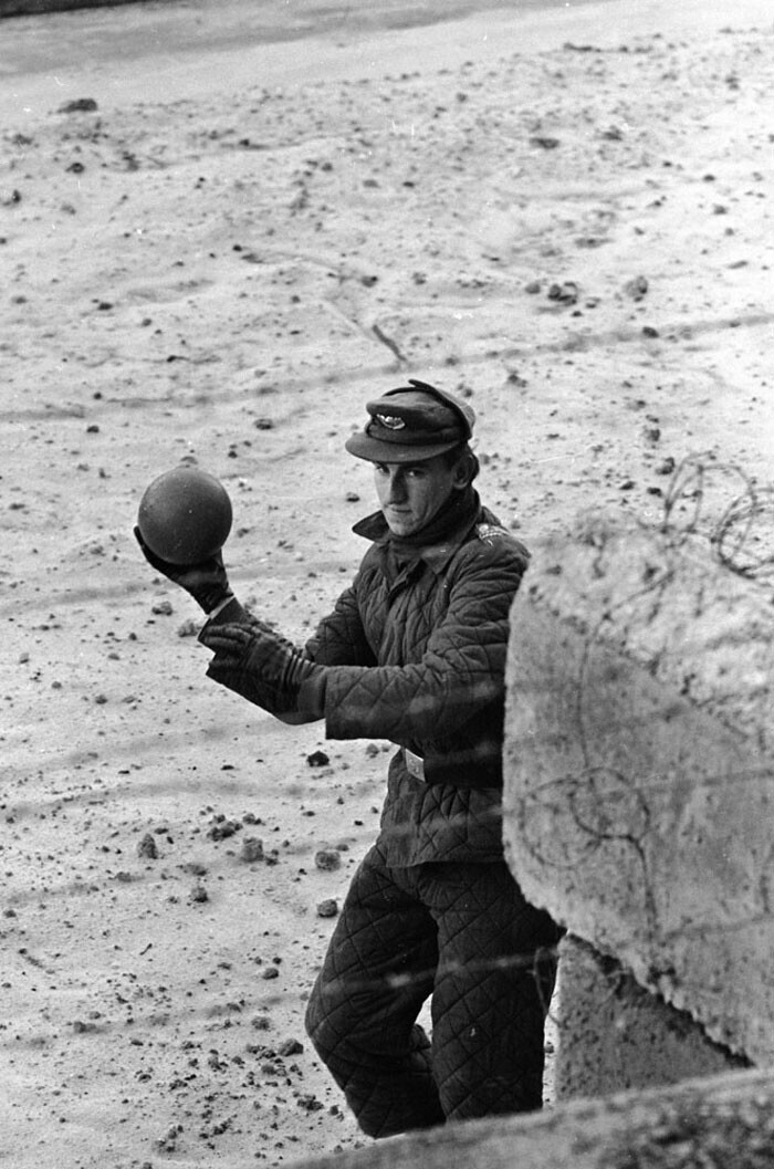 10. Солдат из Восточной Германии бросает мяч ребенку, играющему на западногерманской стороне Берлинской стены. 1962 г.