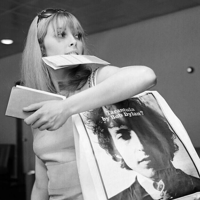 26. Шэрон Тейт в аэропорту Хитроу, Лондон, с сумкой, рекламирующей книгу стихов Боба Дилана "Тарантул". 1966 год