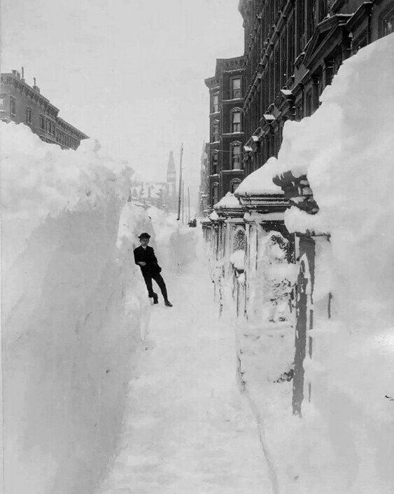 Молодой человек, стоящий в зачищенном от снега районе на Мэдисон-авеню и 40-й улице в Нью-Йорке.