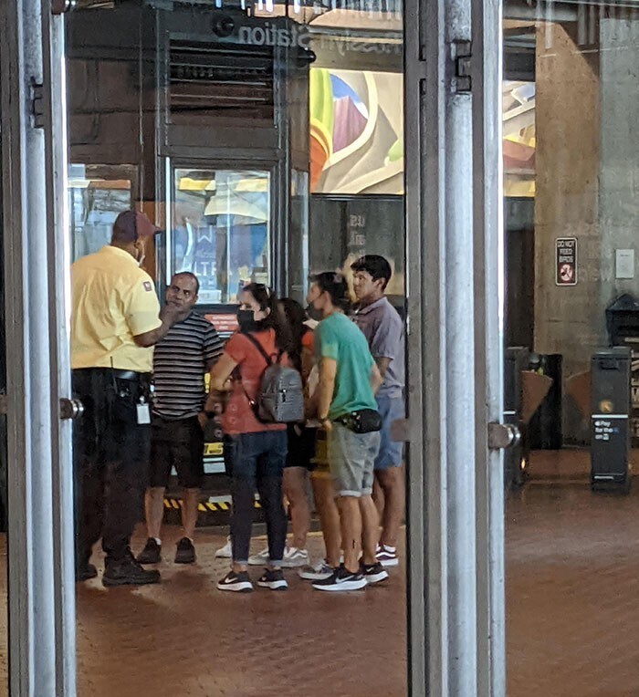 Служба охраны делает выговор туристам за то, что они нажали кнопку экстренной остановки на эскалаторе метро, чтобы сделать селфи
