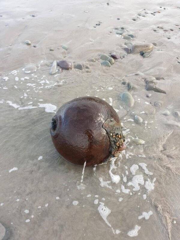 Ржавый железный шар с отверстием, найденный на пляже
