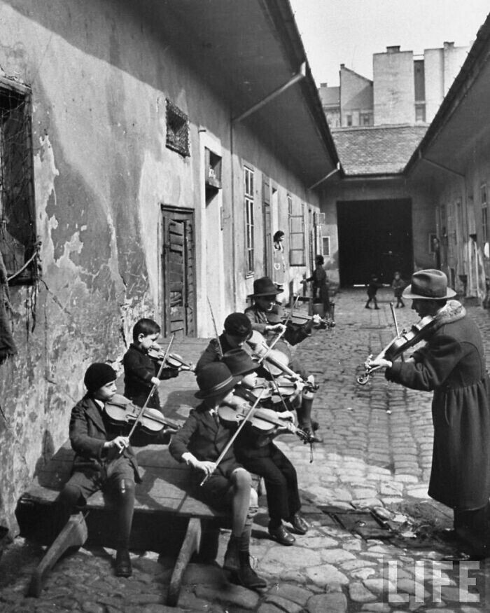 Цыганских детей учат игре на скрипке в одном из бедных дворов. Будапешт, Венгрия, 1939 год