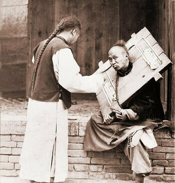 Китаец кормит преступника в канге (устройство для публичного унижения и наказаний), 1905 год
