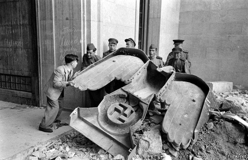 Немец помогает советским солдатам демонтировать бронзового нацистского орла с...