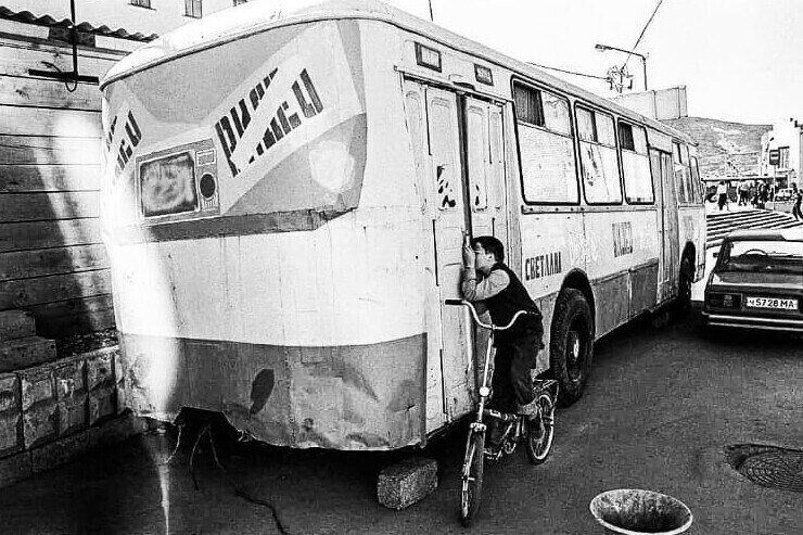 Мальчик подсматривает за показом фильма в видеосалоне, который находится в автобусе, Магадан, 1994 год