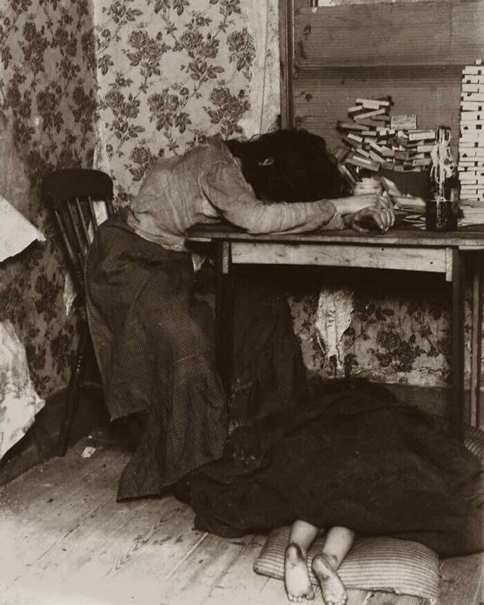 7. Молодая мать, измученная долгими часами изготовления спичечных коробков. У ее ног спит младенец, укрытый одеялом. Уайтчепел, Лондон, примерно 1890 год
