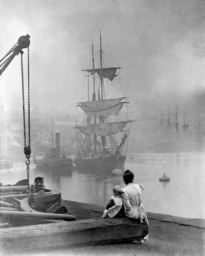 26. Мать и дочь смотрят, как высокий корабль плывет по Темзе с помощью парового буксира, Лондон, 1880 год