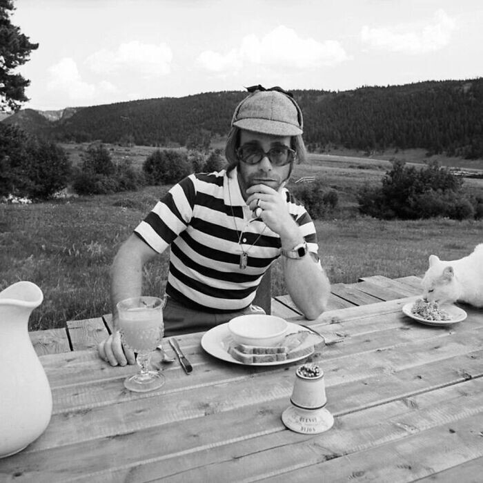 Молодой Элтон Джон и котик, поедающий с тарелки, 1974