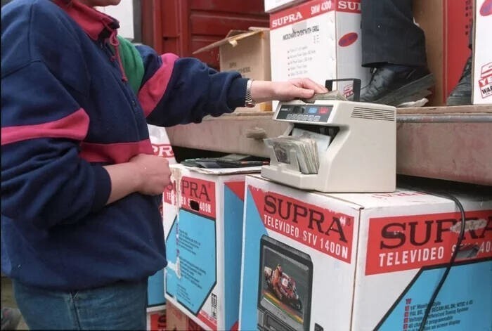 Продавец пересчитывает деньги перед продажей видеодвойки на рынке, 1990-е годы.