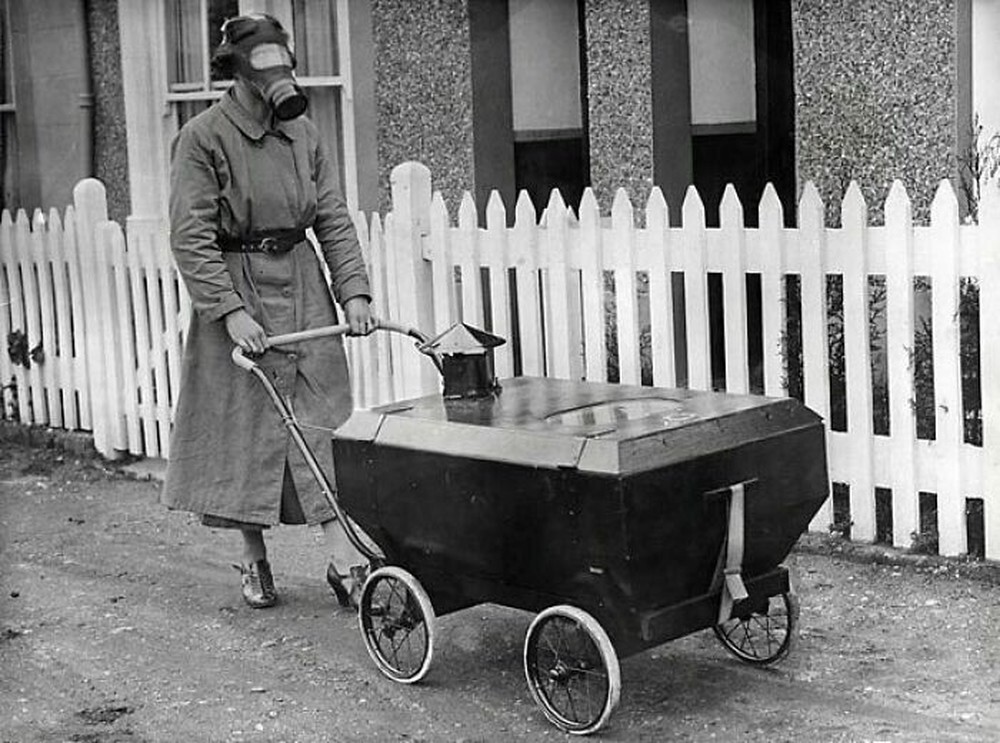 20. Женщина в противогазе прогуливается с противогазовой коляской в Англии, 1938 год
