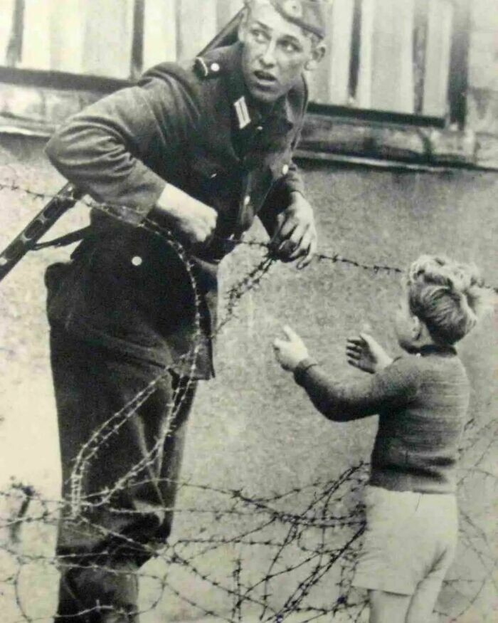 2. Немецкий солдат помогает мальчику пересечь Берлинскую стену в день, когда она была возведена, 1961 год