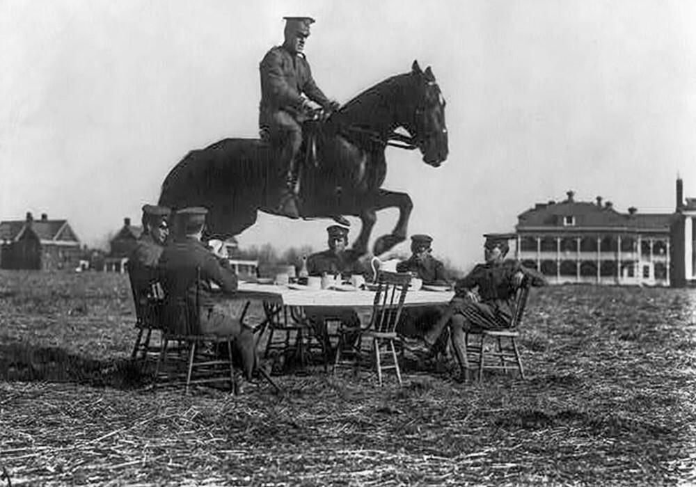 23. Солдаты армии США сидят вокруг стола, пока один из них перепрыгивает через него верхом на лошади 