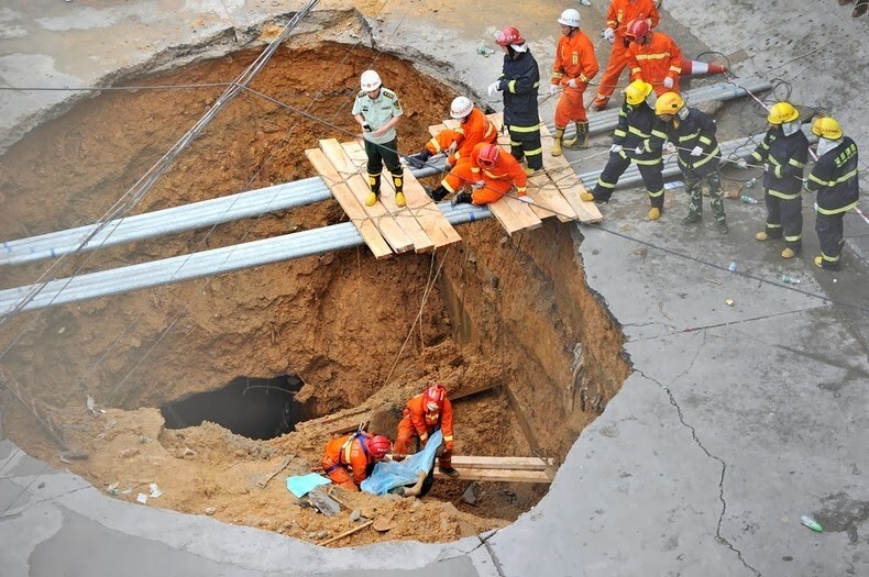 4. Спасатели достают тело пострадавшего из ямы на дороге в китайском Шэньчжэне. 21 мая 2013 года