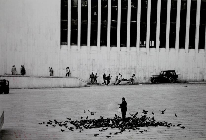 1. 6 ноября 1985 года 35 партизан ворвались во Дворец правосудия, Колумбия, убив администратора и нескольких сотрудников службы безопасности и взяв в заложники 300 человек. На этом фото мужчина кормит голубей, на фоне спасательной операции