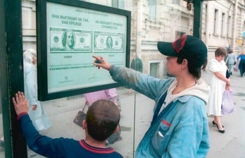 Дети рассматривают информационный постер о новом дизайне 100-долларовой банкноты.