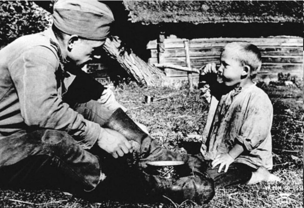 Советский солдат кормит мальчика кашей из своего котелка
