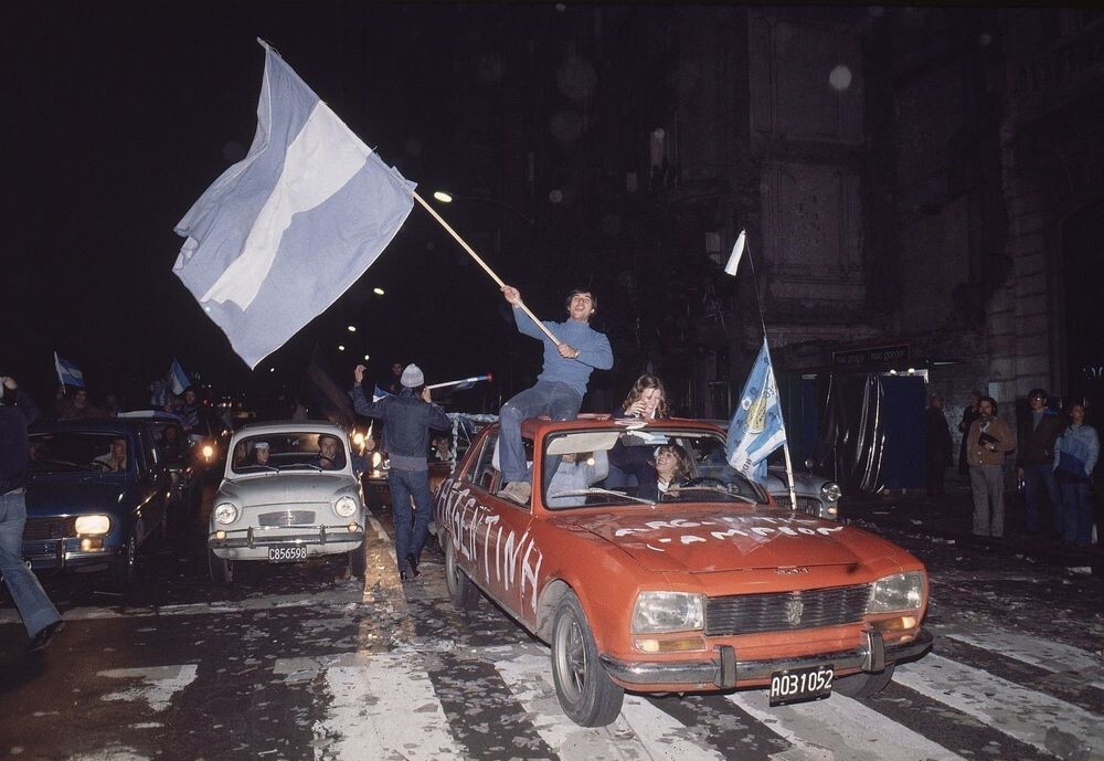 Аргентинские болельщики празднуют на улице с флагами после победы в финале чемпионата мира по футболу против Нидерландов. Буэнос-Айрес, Аргентина, 1978 год