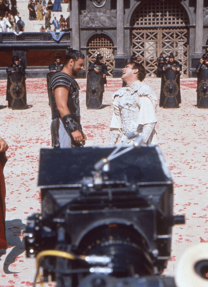 24. Рассел Кроу с сигаретой в руке и Хоакин Феникс смеются во время съемок финальной дуэли из «Гладиатора» (1999)