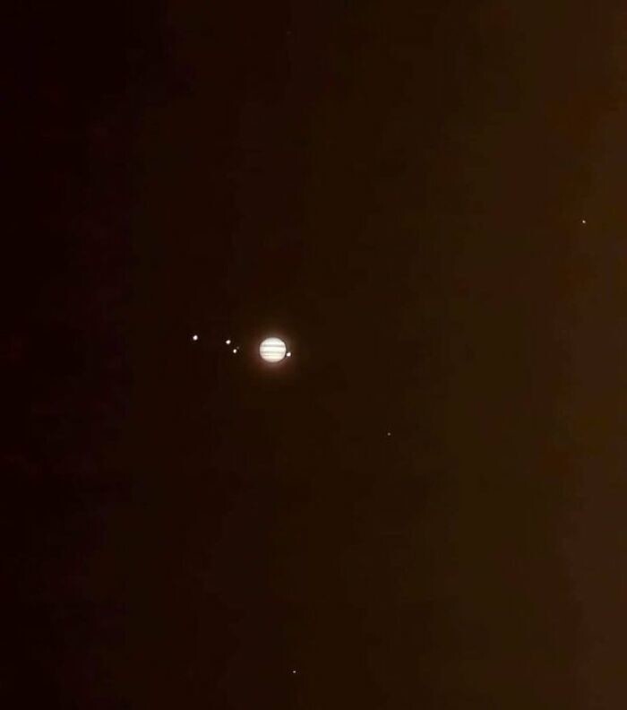 4. Юпитер и его четыре крупнейших спутника, светящиеся в ночном небе. Ганимед, Европа и Каллисто слева, Ио справа