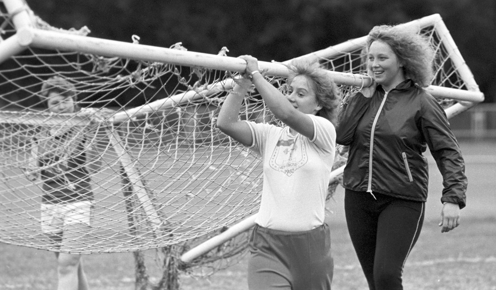 Игроки женской команды по футболу устанавливают ворота на футбольном поле (1987)