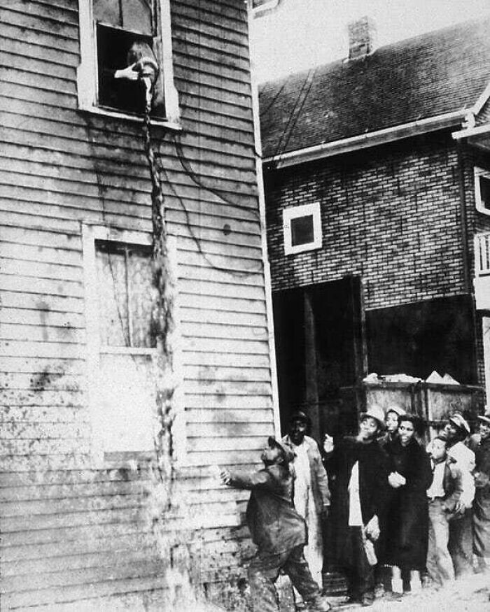 28. Мужчина пытается набрать в стакан самогона, который выливает полиция в эпоху сухого закона. 1925