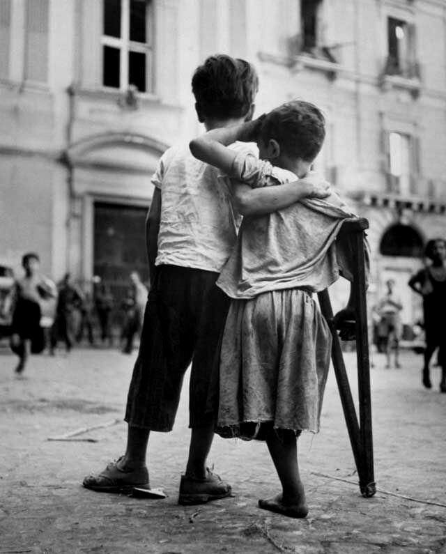 20. Мальчик помогает своему младшему брату, потерявшему ногу во время бомбардировки Неаполя. Италия, 1944