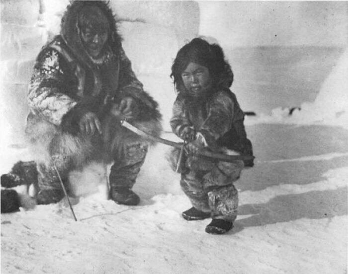 20. Мужчина-инупиат учит маленького мальчика стрелять, Аляска, 1920 год