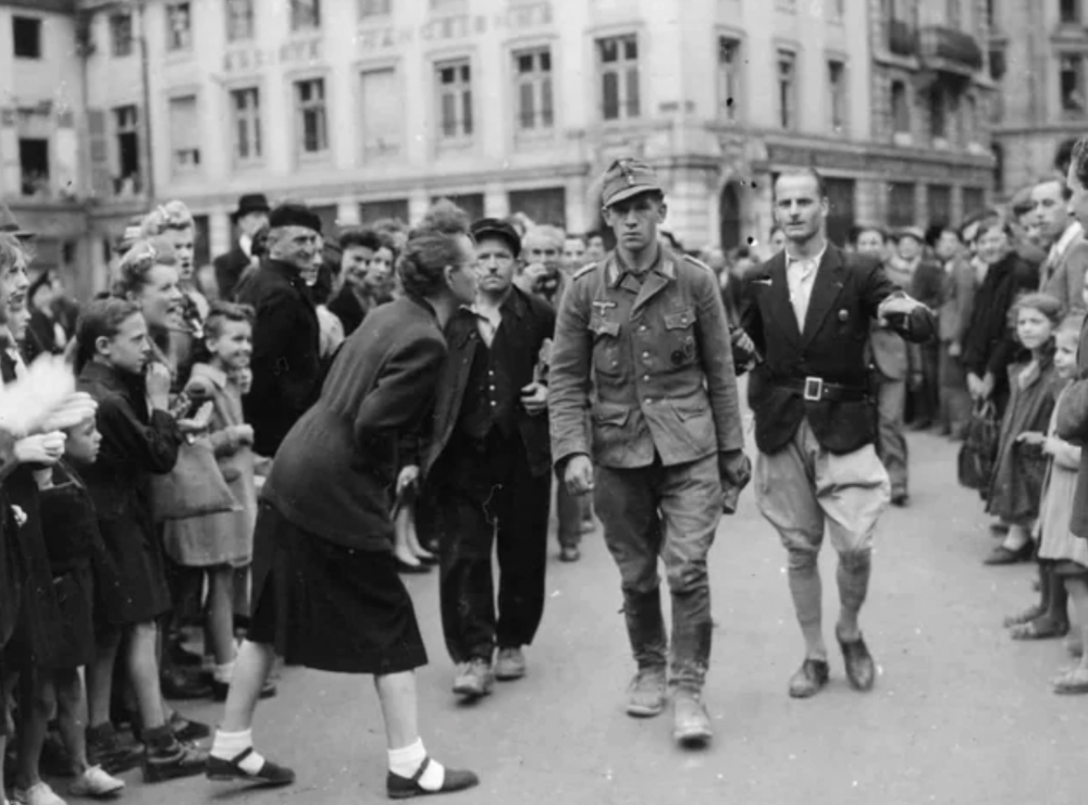 14. Немецкого солдата, пойманного французским сопротивлением, ведут по улицам Сен-Михеля, Франция, сентябрь 1944 года