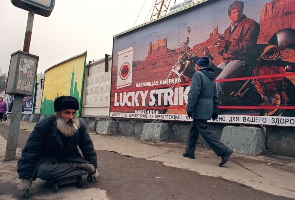 Инвалид на фоне рекламы сигарет «Lucky Strike». Россия, 1990 -е годы.