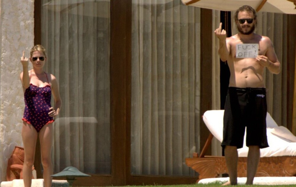 6. Хит Леджер и Мишель Уильямс с табличкой "Отвалите!" в 2006 году