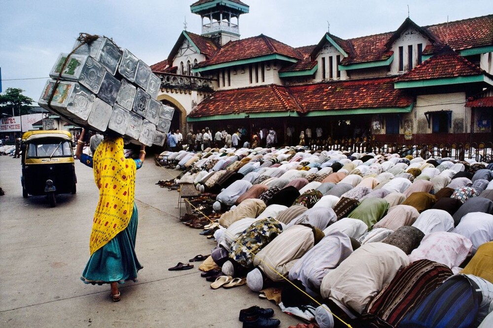 Женщина с грузом проходит мимо сотен молящихся мужчин на железнодорожной станции Бандра в Мумбаи, Индия, 1996 год