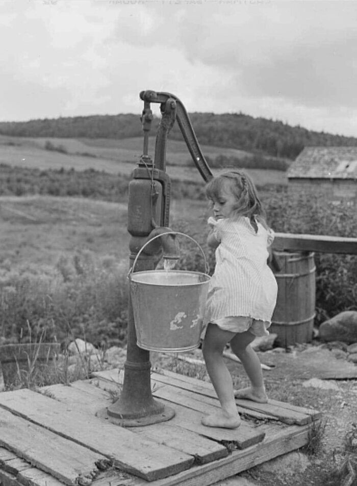 30. Маленькая девочка набирает воду на ферме, штат Мэн, 1942 год