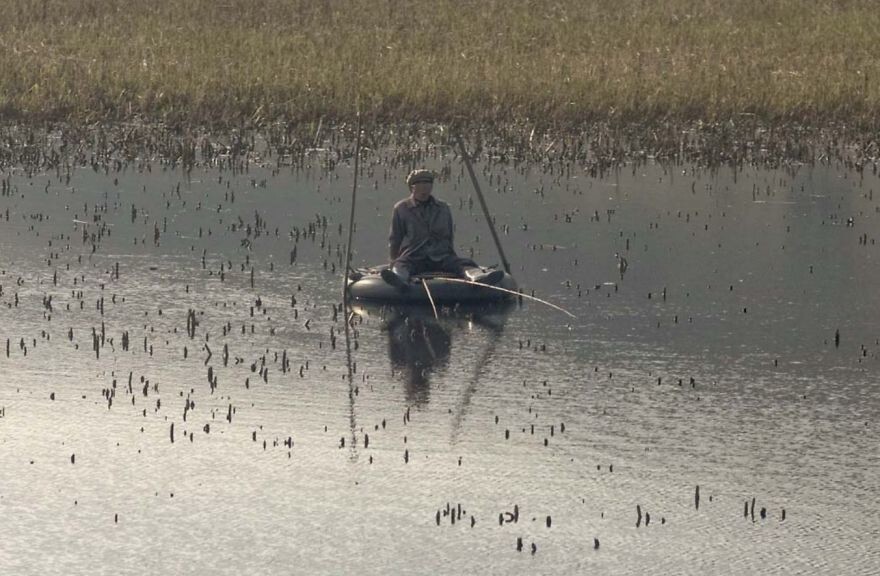 9. Рыбак, использующий шину в качестве лодки на озере по пути в Вонсан