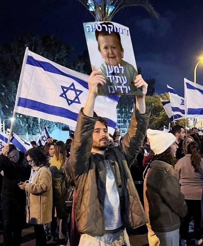 Вот это оралово...Участник израильских протестов с плакатом с надписью «Демократия ради будущего наших детей», на котором изображён 21 летний Хасбик из Дагестана