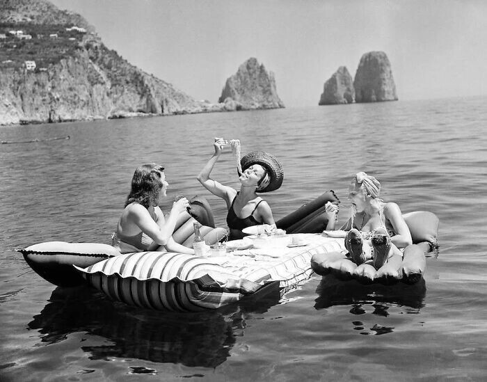 20. Девушки едят спагетти на надувных матрасах на острове Капри, 1939 год