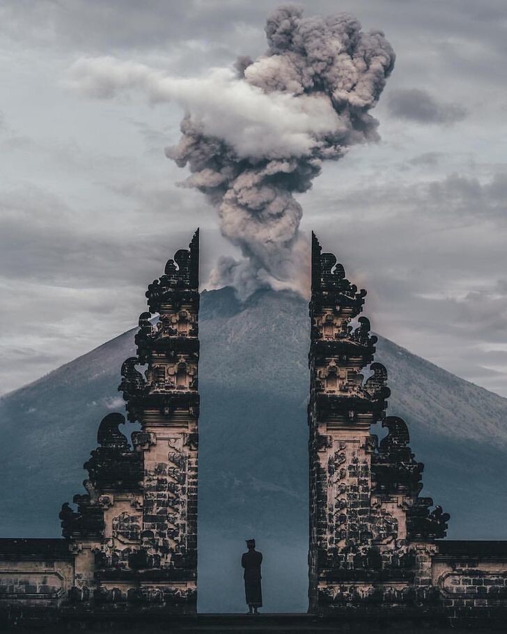 8. Смотритель храма наблюдает за извержением вулкана на Бали