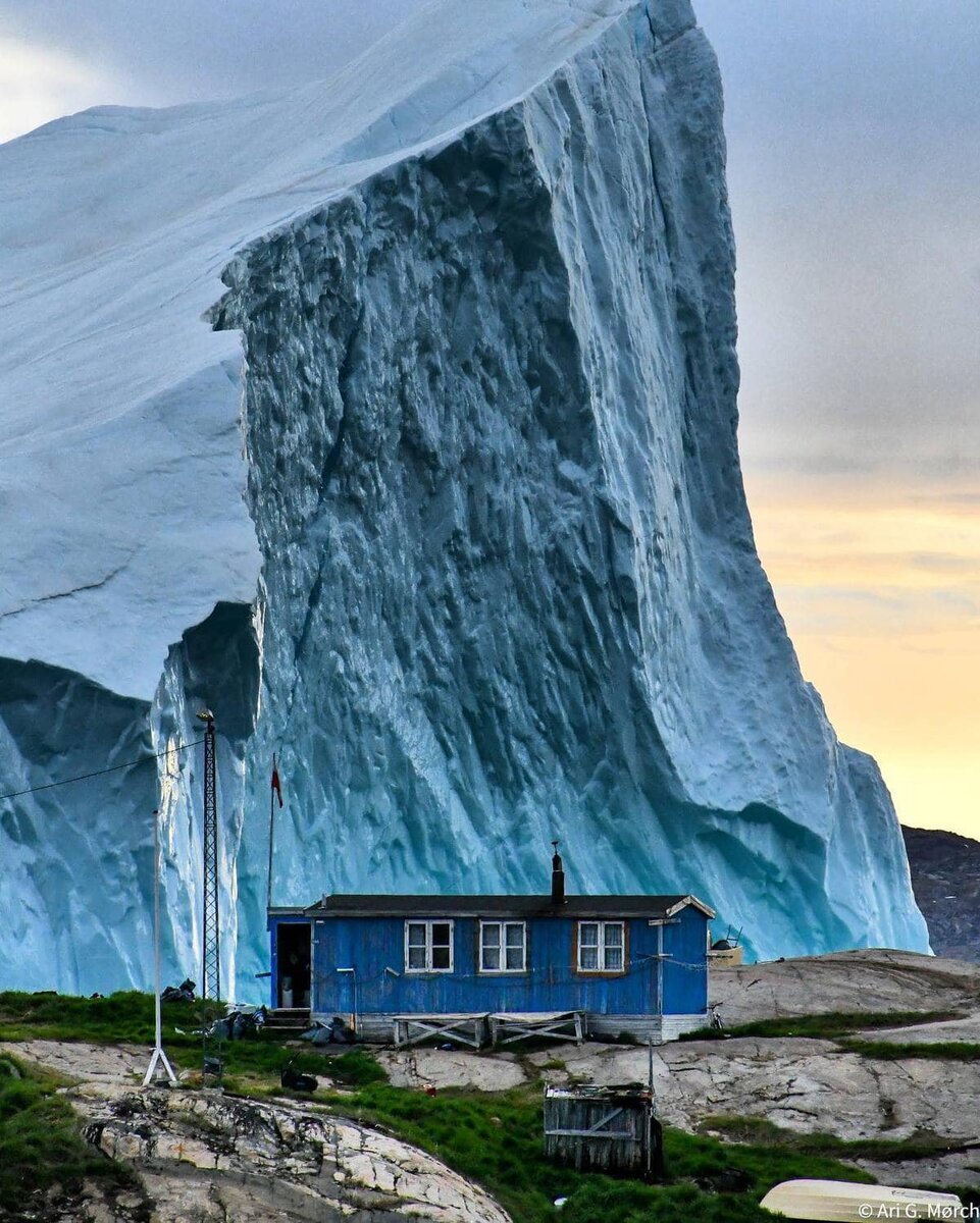 16. Огромный айсберг проплывает мимо домика в Гренландии
