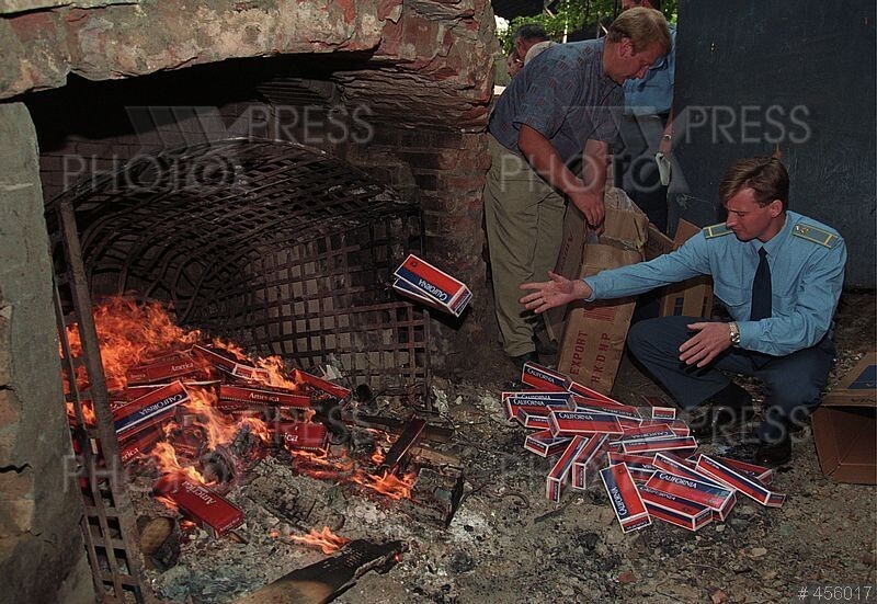 Офицер таможенной службы уничтожает партию контрабандных сигарет в печи московского завода, 17 июня 1996 года.