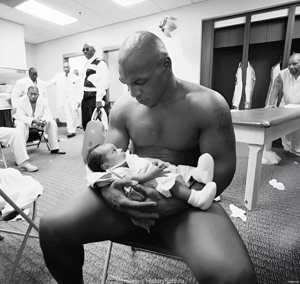 Боксер Майк Тайсон держит своего двухмесячного сына Мигеля в раздевалке после...