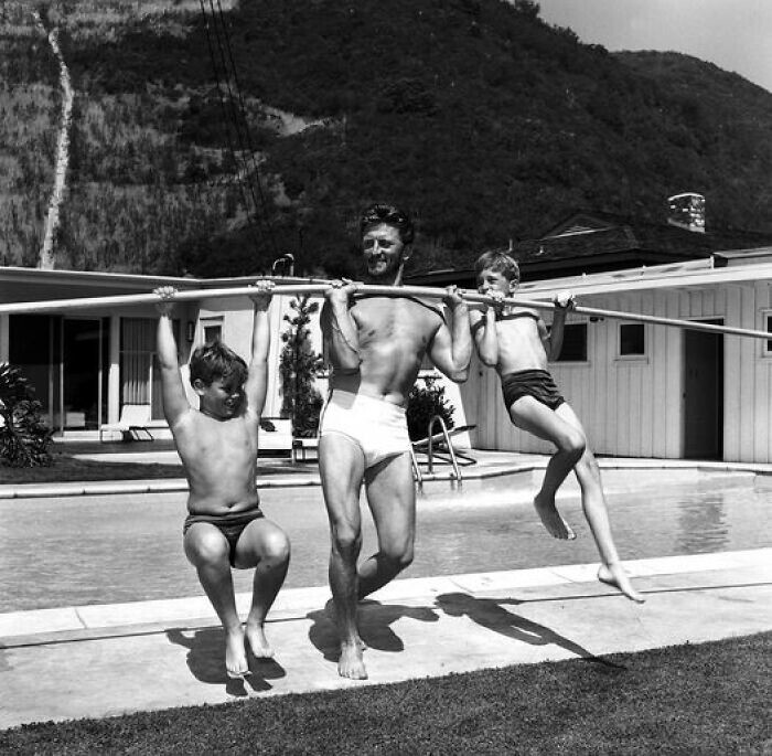 21. Актёр Кирк Дуглас поднимает своих сыновей, Джоэла и Майкла, во время тренировки. Фото 1955 года