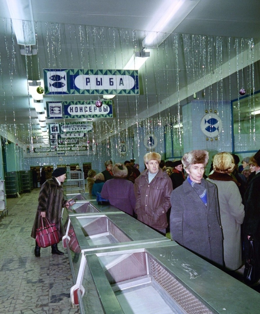 Покупатели проходят мимо пустых морозильных камер универсама и праздничных новогодних украшений в Загорске, 20 декабря 1990 год
