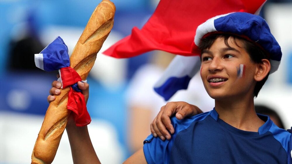 Болельщик сборной Франции поддерживает родную команду с багетом в руках
