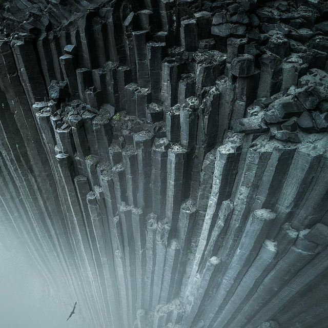 7. Массивные колонны базальтовых скал высоко над туманом в Исландии. Эти столбы созданы базальтовой лавой, которая охлаждается иначе, чем обычная лава, в процессе, называемом столбчатым соединением, создавая таким образом эти формы