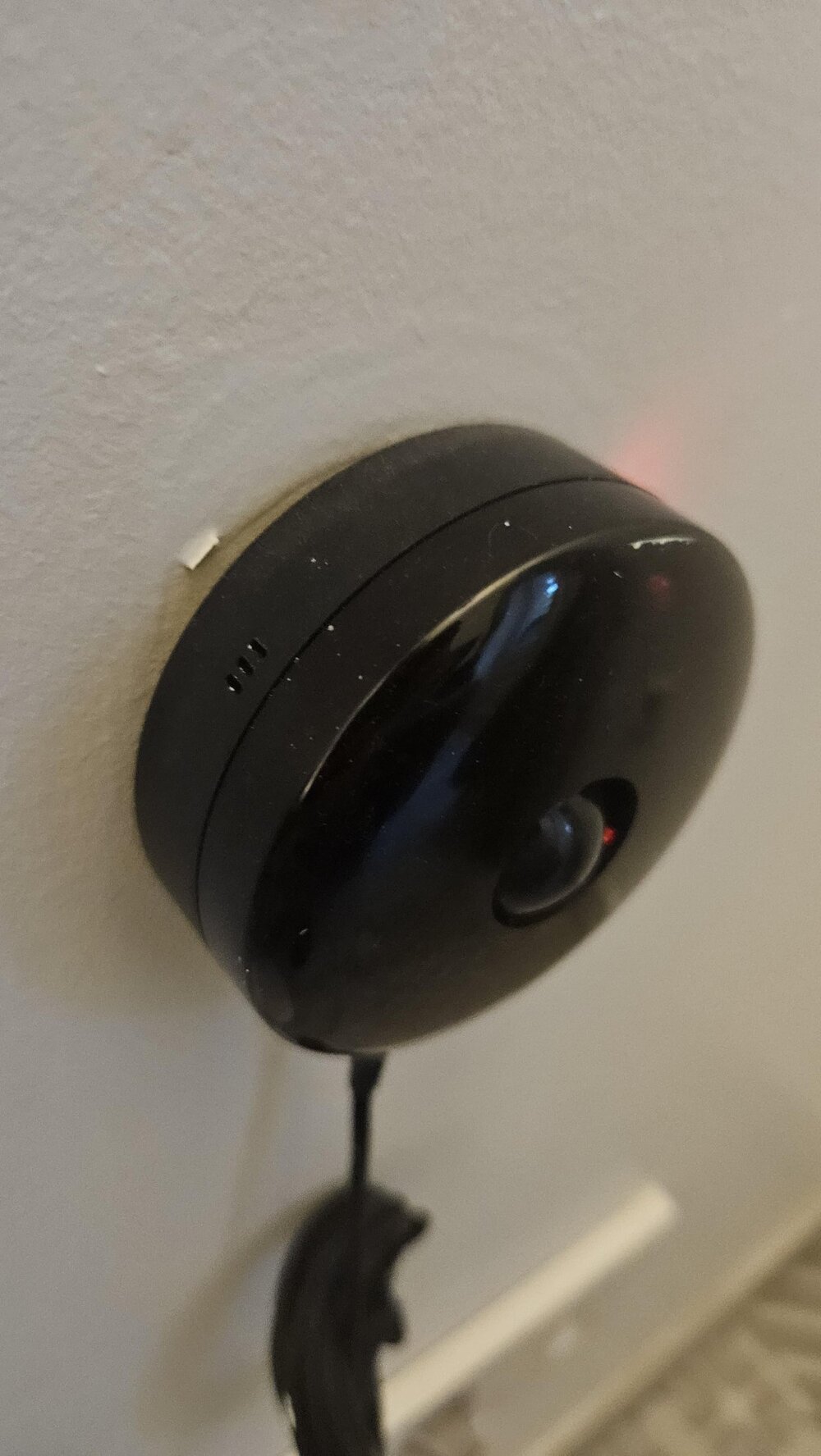 «Круглое чёрное электронное устройство на стене в комнате. Шарик в центре немного двигается»
