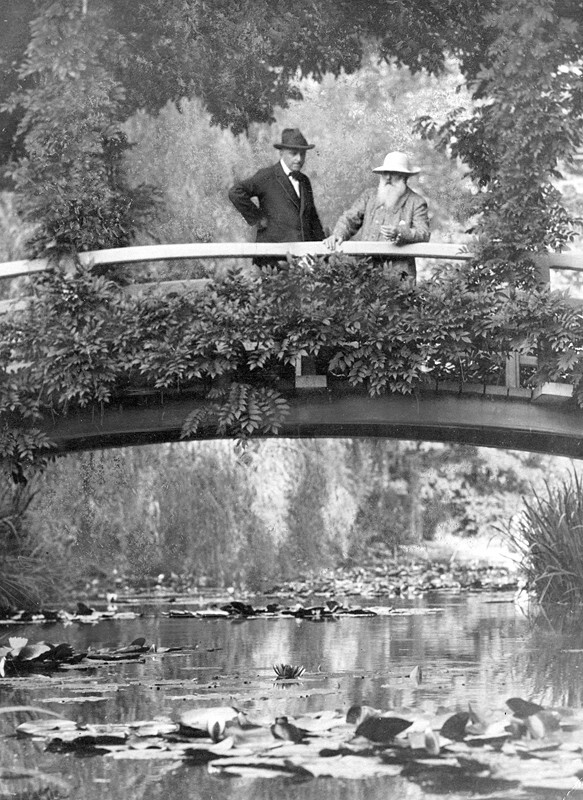 10. Знаменитый французский художник-импрессионист Клод Моне стоит на мосту с посетителем в своем саду в Живерни, Франция, 1922 год
